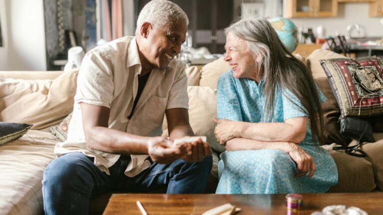 a man rolling a joint on a couch beside a woman