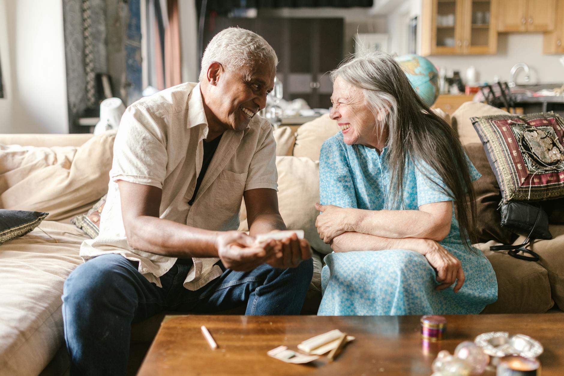 a man rolling a joint on a couch beside a woman