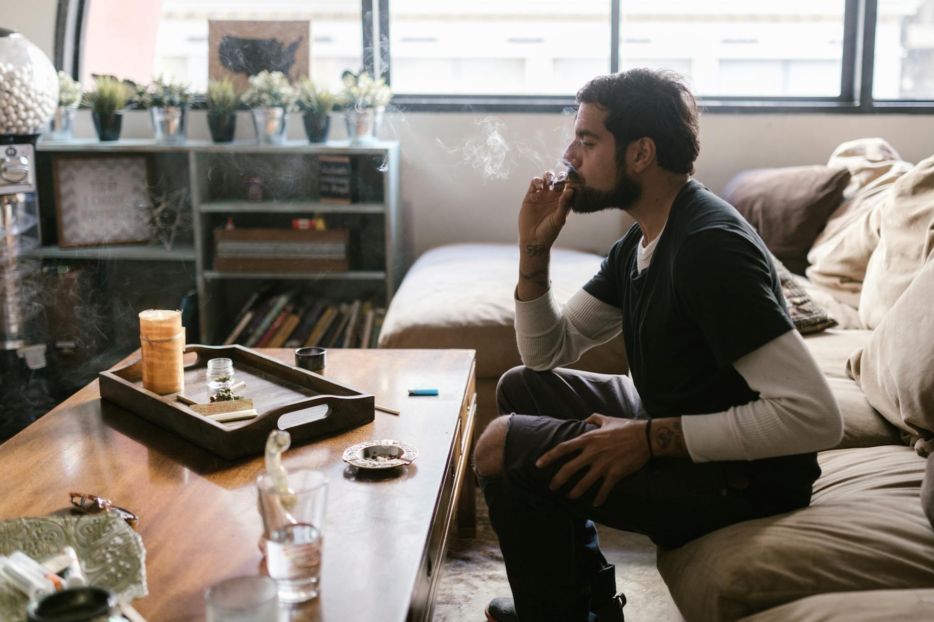 a bearded man sitting on the couch while smoking weed